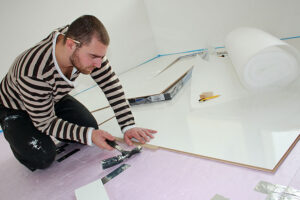 man installing laminate flooring in home
