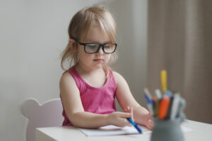 small funny girl in eyeglasses writing and drawing