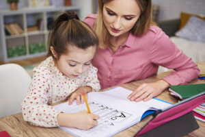 Young woman helping girl with homework